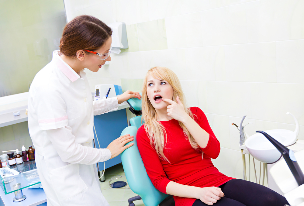 woman in red top points out source of dental problem
