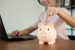 woman putting coin in piggy bank